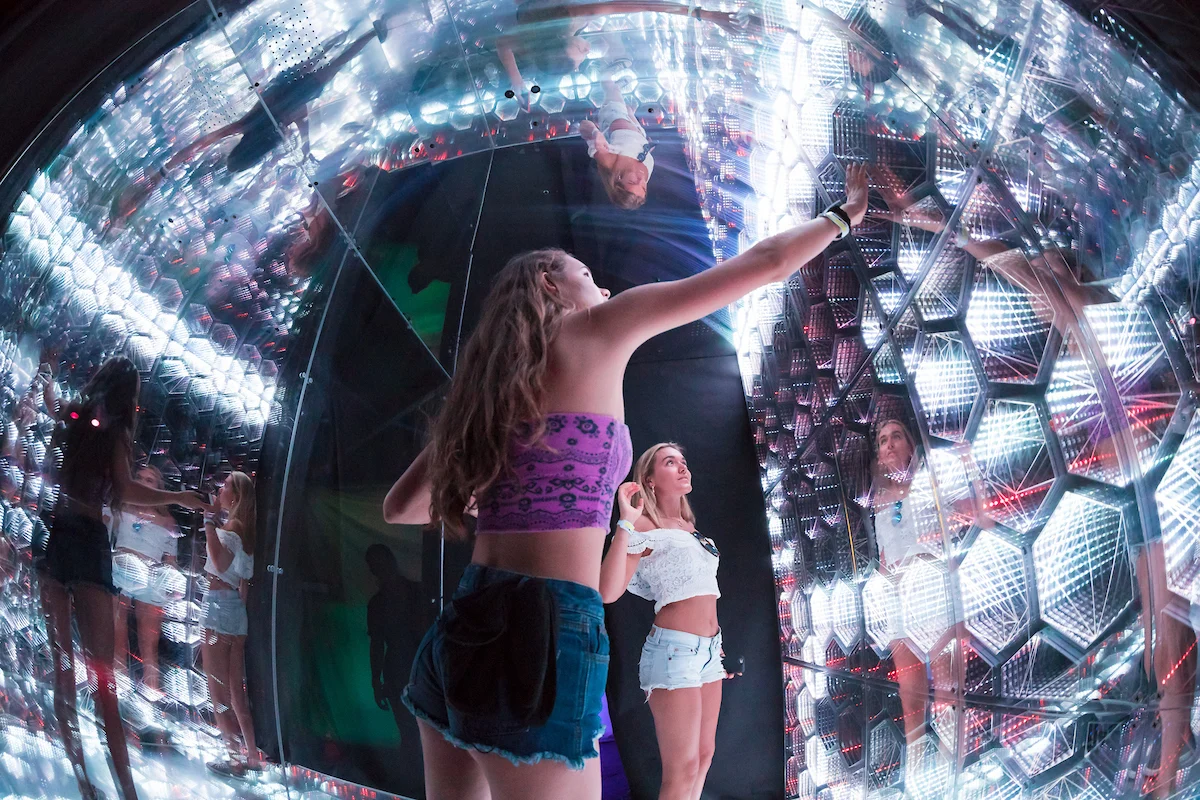 A visitor reaching into a mirrored installation