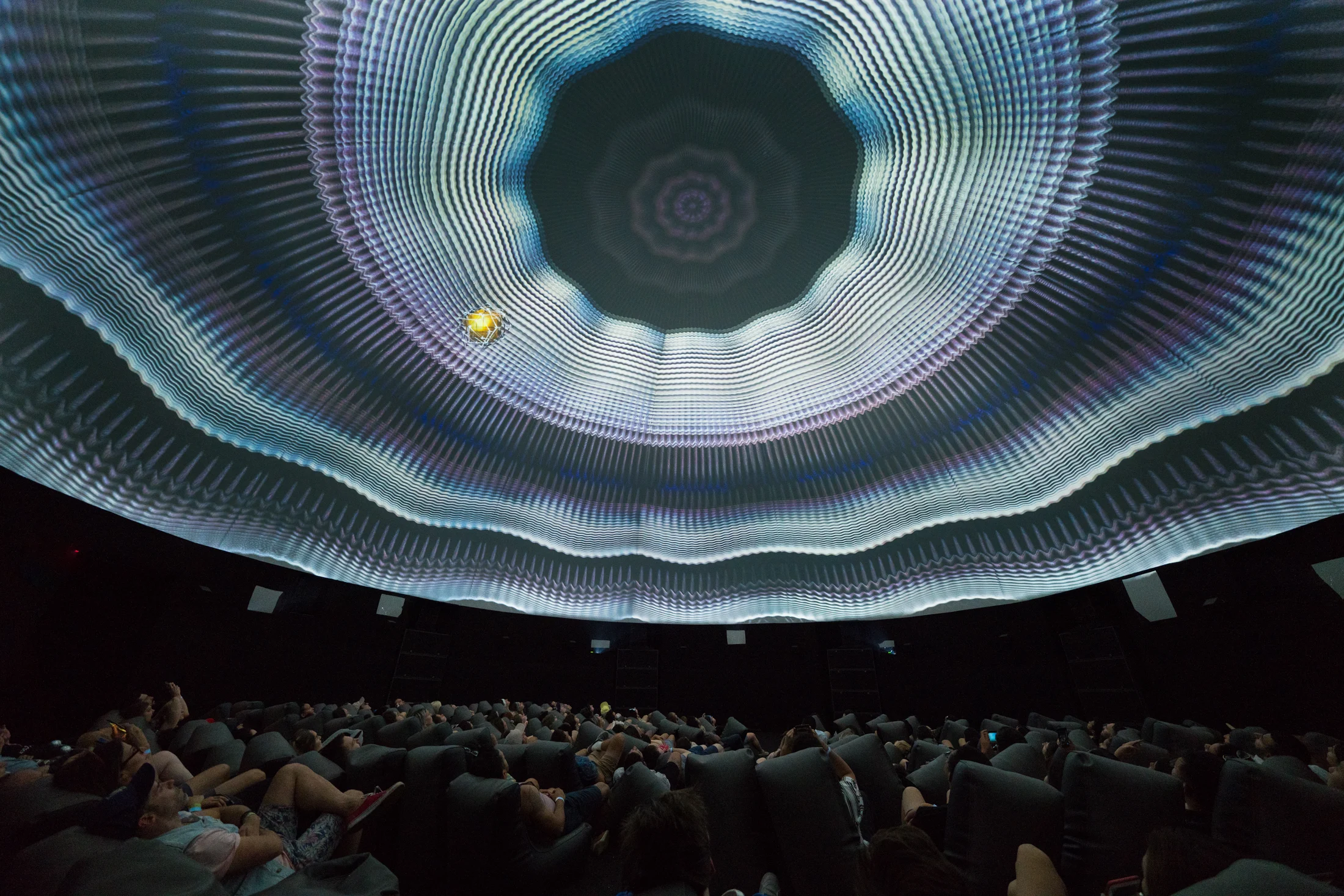 A crowd beneath a sweeping dome projection